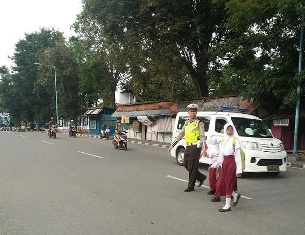 Polisi membantu menyebrang anak sekolah